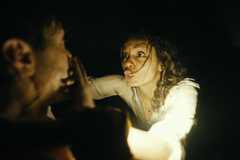 Georgina Campbell as Tess Marshall shushes Justin Long's AJ Gilbrand. They sit in a dark, dimly lit room.Image from Barbarian from 20th Century Studios.